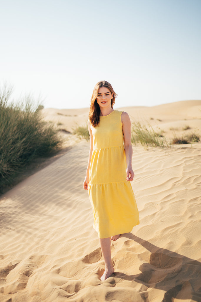 Woman standing in a yellow linen dress.