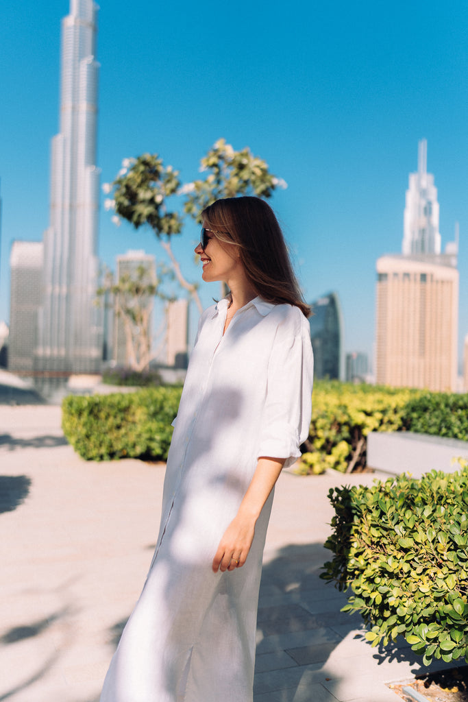 Woman standing in front of Burj Khalifa in a white linen dress.